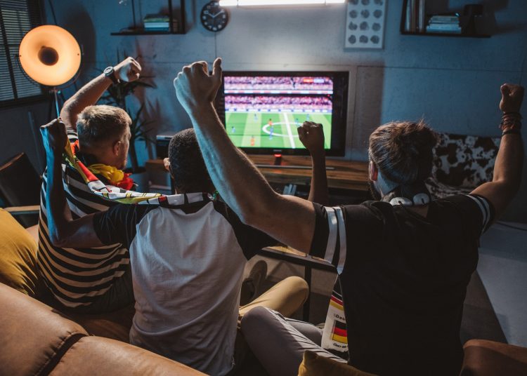 φίλοι παρακολουθούν ποδοσφαιρικό αγώνα στην τηλέοραση