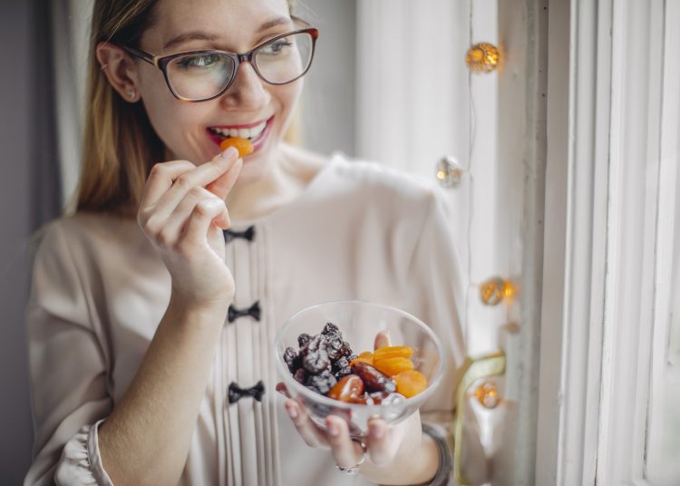 γυναίκα τρώει αποξηραμένα φρούτα